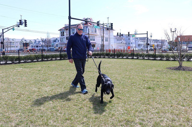 Sean Barnes, with his dog, Harbor, during a brisk walk in April, says that he is pleased with the dredging progress in Snug Harbor. 