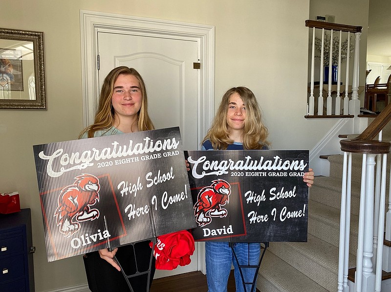 Graduating twins Olivia and David Heap proudly display their lawn signs.