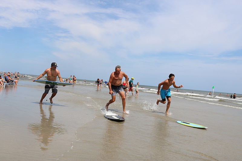 George Groves, center, his son, Jeff, left, and his grandson, John, all of Bensalem, Pa., use their skim boards to enjoy the ocean during the oppressive heat Monday.