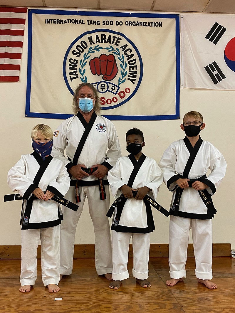 Miles O’Hara, at left, another class participant, and Michael Stankiewicz pictured with their instructor after receiving their black belts.