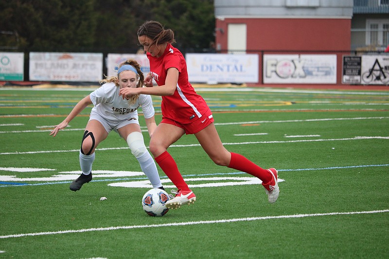 Faith Slimmer (in red) dribbles through an Absegami player on the way to her four-goal performance.