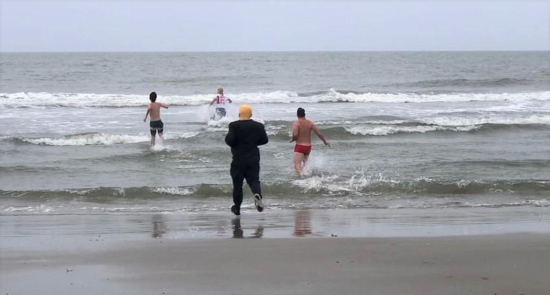 Carl Wanek and Joe Schneider follow Wanek's son, Carl Jr., and friend Tripp Crowley into the waves for their traditional "First Dip" on New Year's Day in 2021.