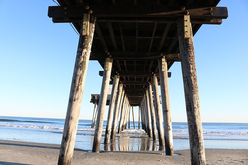 A view underneath the pier shows the massive timber piles that serve as its support structure.