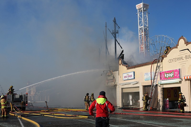 Firefighters spray water on the Boardwalk entrance of Playland's Castaway Cove to extinguish the blaze.