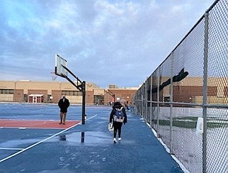 A school employee watches as students walks to the school.