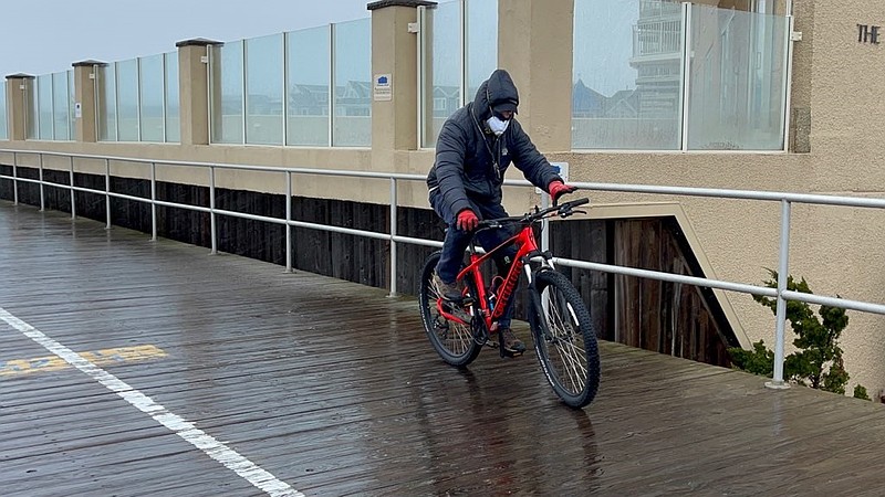 The bicyclist is one of just a few people out on the chilly, stormy day.