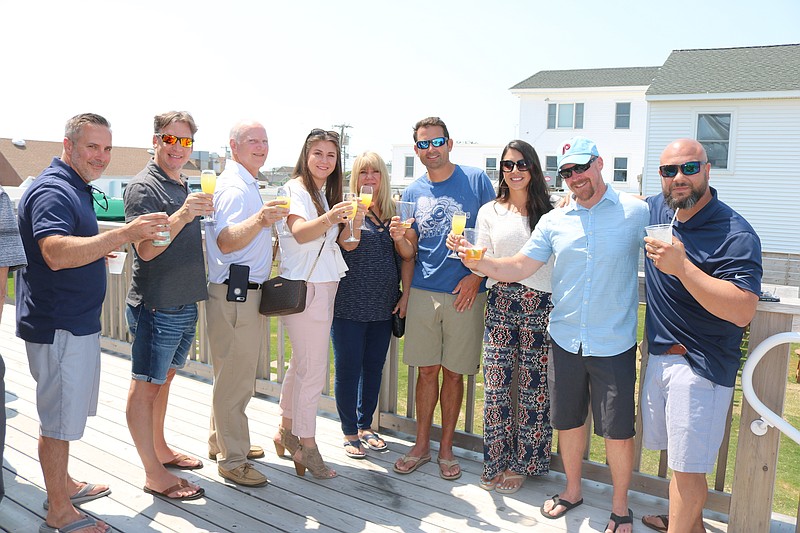 Customers join in a group toast at the beach bar to celebrate the unveiling of the Deauville Inn's new upgrades.