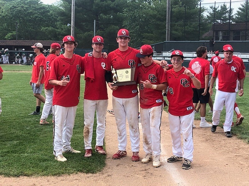 Members of the Ocean City High School baseball team hold a championship plaque while celebrating their title.