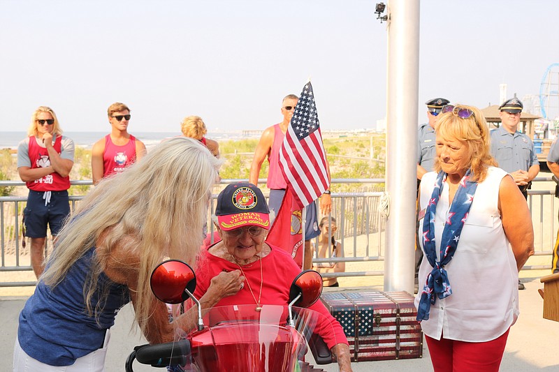 Sue Barnes puts a Marine Corp. pin on her mom's shirt as Commissioner E. Marie Hayes looks on at the 2021 ceremony.