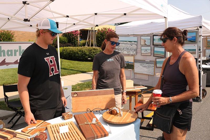 Pierre Koenig, of Newtown Square, Pa., of SawShark, and his mom, Denise Koenig, center, chat with a customer. 