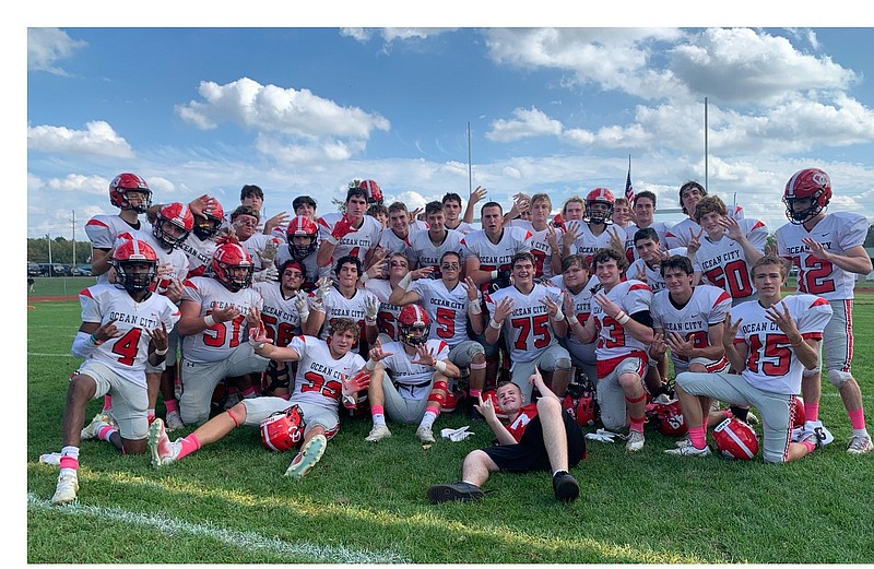 Ocean City's players each hold up seven fingers to celebrate their perfect 7-0 record. (Twitter photo)