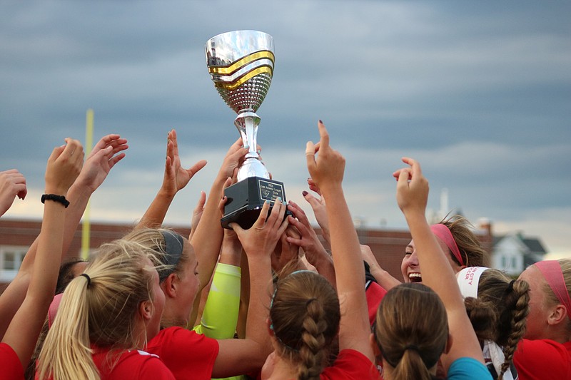 The team hoists the conference championship  trophy.