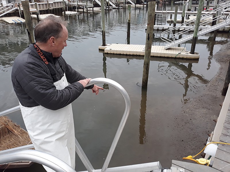 Sean Barnes points to the sediment buildup, a year after the slips were dredged.