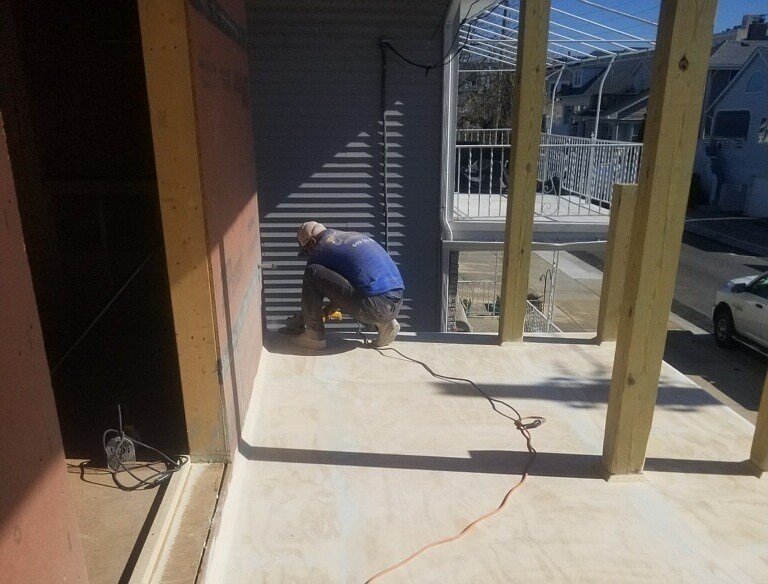 A crew member at Coat the Coast helps install coating on a new deck.