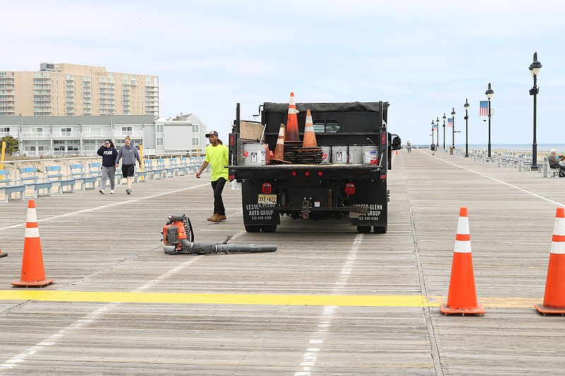 Workers get ready to paint the lines to delineate between bike and jogging lanes on the boards.