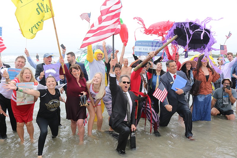 John Walton, center, holding flag, and fellow business people celebrate their march into the ocean in 2022.