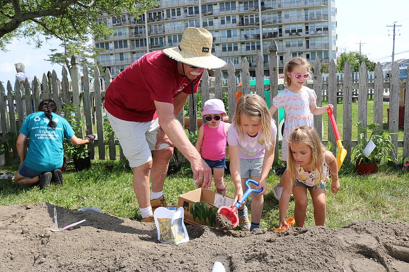 Ocean City Environmental Commission Chairman Rick Bernardini shows preschoolers how to scoop out a hole for the butterfly plants at Bayside Center.