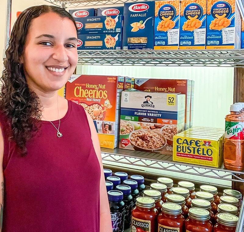 Samantha Kurtz-Seif, director of Social Services for Ocean City, stands beside shelves stacked with food.