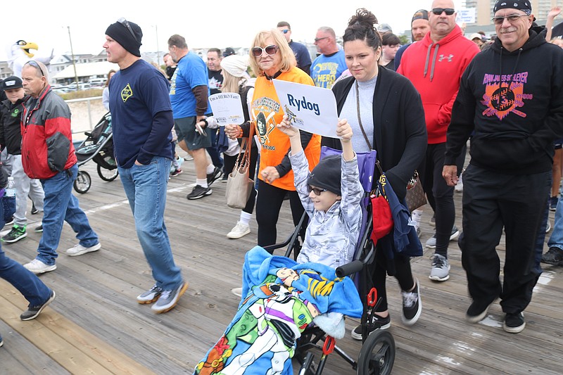 April McCrane, of Manchester Township, and her husband Jim, in red sweatshirt) walk with their son, Carter, who holds up a sign for Ryan Schleyer, "Ry Dog."