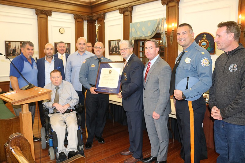 A certificate of accreditation is presented during a ceremony in City Council Chambers.