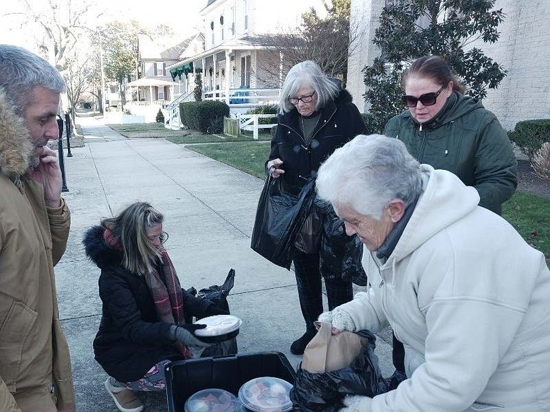 Community Christmas Dinner organizer Kathy Thompson places food in a container with help from other volunteers.