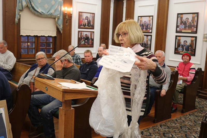 Dorie Good holds up a bag of trash from a construction project near her home.