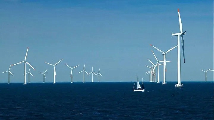 This image depicting Orsted's Nysted Wind Farm in Denmark shows the massive size of the offshore wind turbines compared to a sailboat. (Photo credit Orsted.com)