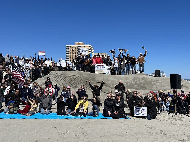 Advocates to save the whales gather in front of the sand sculpture.