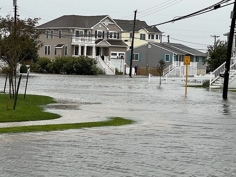 Homeowners look out at the flooding in a neighborhood during high tide.