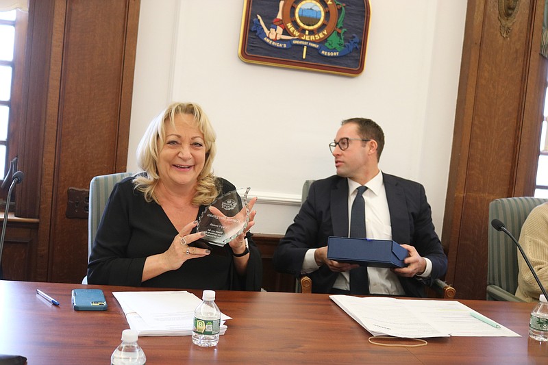 Karen Bergman accepts an inscribed glass plaque presented to her by Council President Pete Madden, at right.