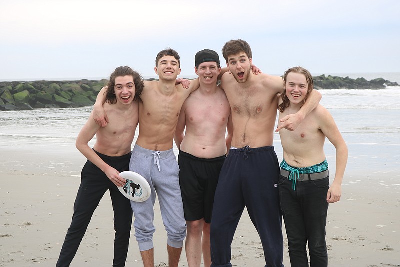 Emery Whitescarver, second from left, and fellow Rowan University students enjoy a game of Frisbee before surfing in Ocean City Saturday.