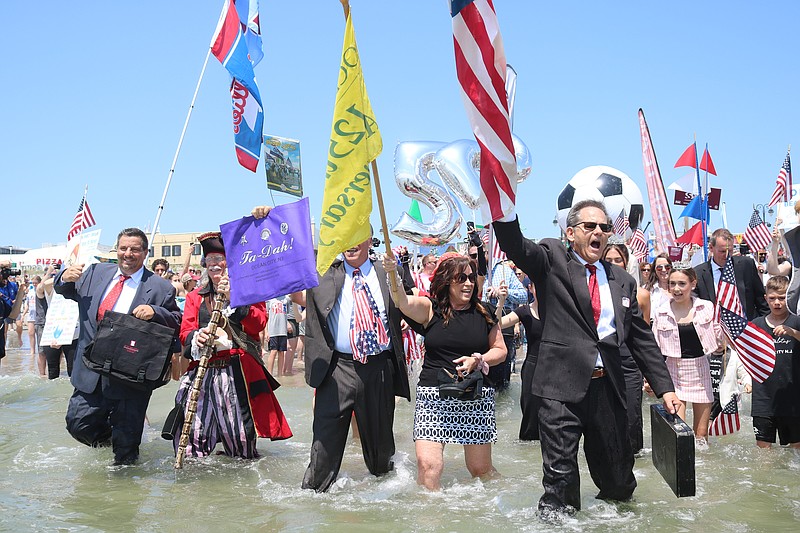 Business Persons Plunge organizer John Walton holds the American Flag as he leads the march into the water for Business Persons Plunge.