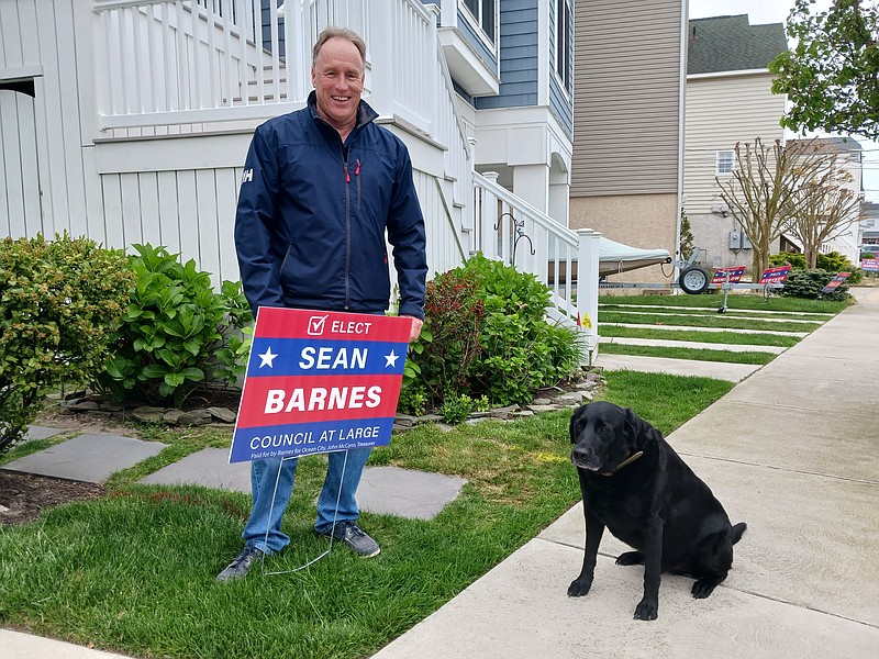 Sean Barnes stands next to a campaign sign and his dog, Harbor, at his home on Revere Place.