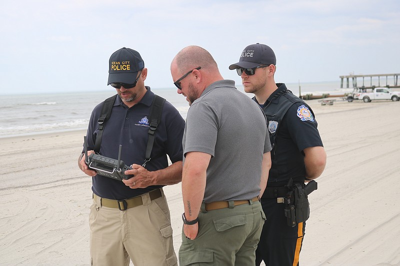 Officers look at the controls as one flies the drone.