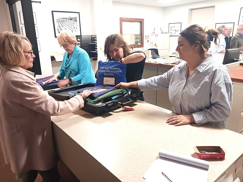 City Clerk Melissa Rasner, right, and other staff collect voting machine cartridges Tuesday night after the polls close. 