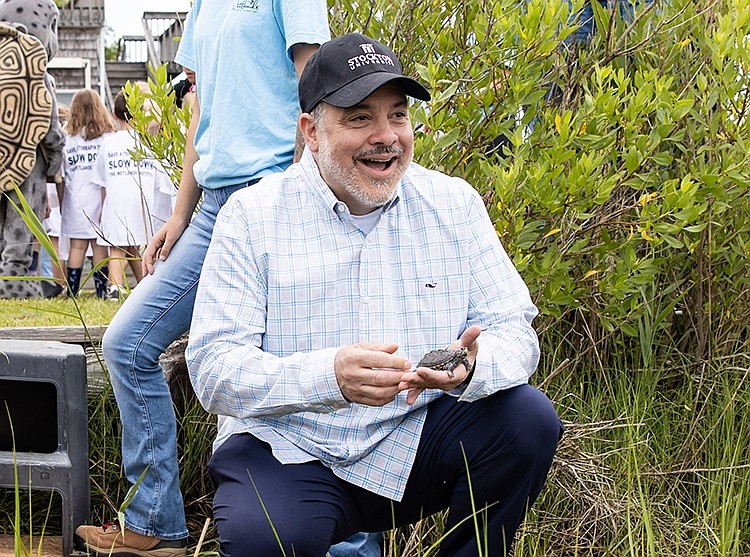 Stockton University President Joe Bertolino laughs as he’s about to release one of the terrapins back into the wild.