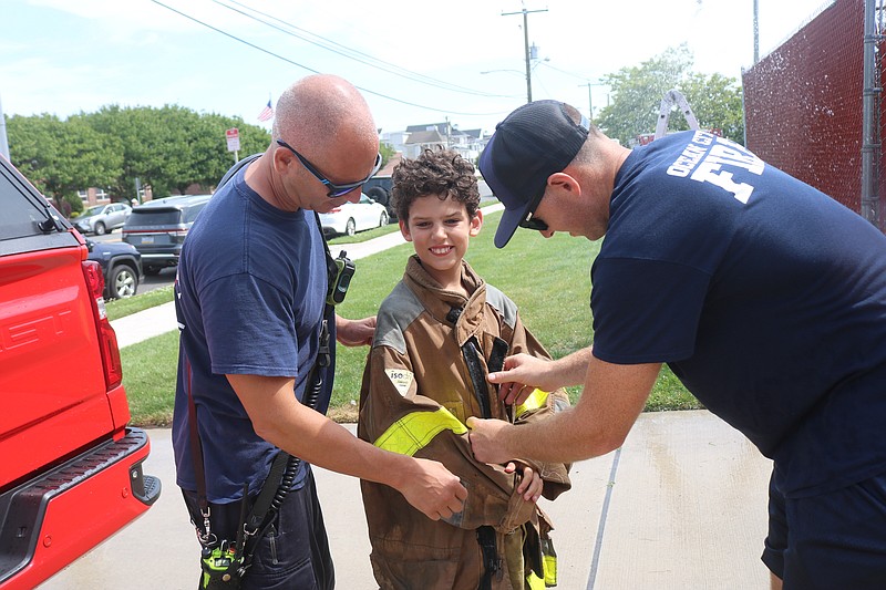 Firefighters give Henry Parks a little helping getting on his fire gear to shut down the sprinkler.