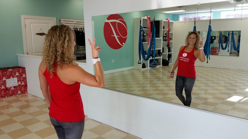 Cicitta gazes at herself in a large mirror in her workout studio.