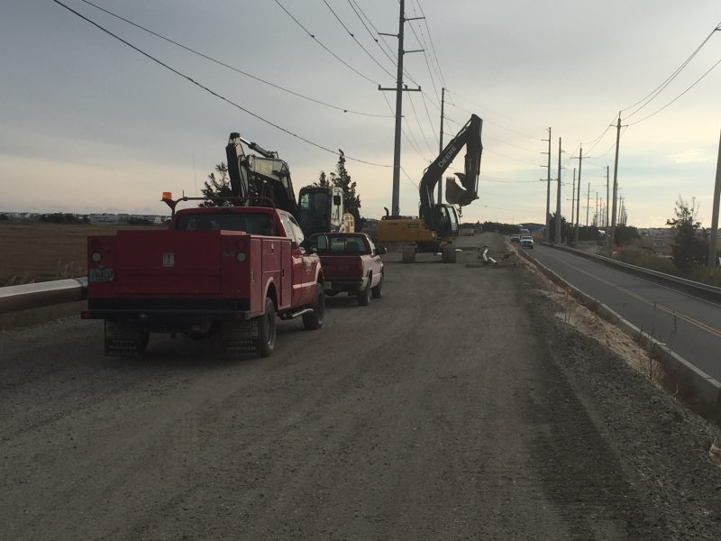 Construction vehicles and equipment line the dirt embankment where the elevated roadway will be built.