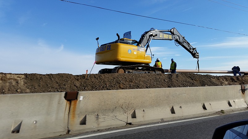 A giant excavator uses its claw to dig out a place for a gas main.