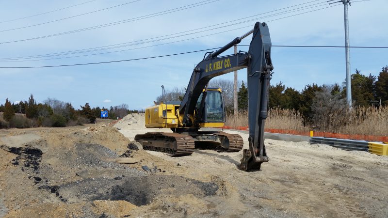 Heavy construction equipment is being used to install a new sewer pipeline underneath the road.