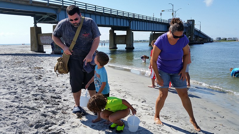 Vacationers Steve and Kindre Kearney, of Woodlyn, Pa., help their children, Maya, 7, and Shane, 4, search for sea shells.