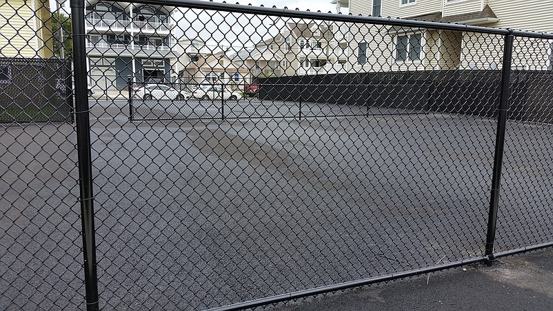 Surrounded by a perimeter fence, the courts need their nets put up before they are ready for players.