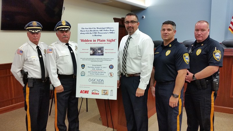 Sea Isle Police Chief Thomas D'Intino, third from right, and other senior law enforcement officials stand in front of a poster promoting the "Hidden in Plain Sight" drug forum.