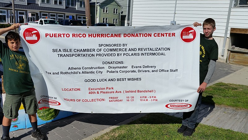 Boy Scout Troop 76 members Antonio "Ducky" Ayala, 12, of Woodbine, and Sam Day, 13, of Dennis Township, hold a banner listing the sponsors involved in the hurricane relief drive.