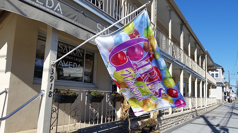 Colorful flags bearing the words "Girls Weekend" fly outside the local businesses participating in the event.