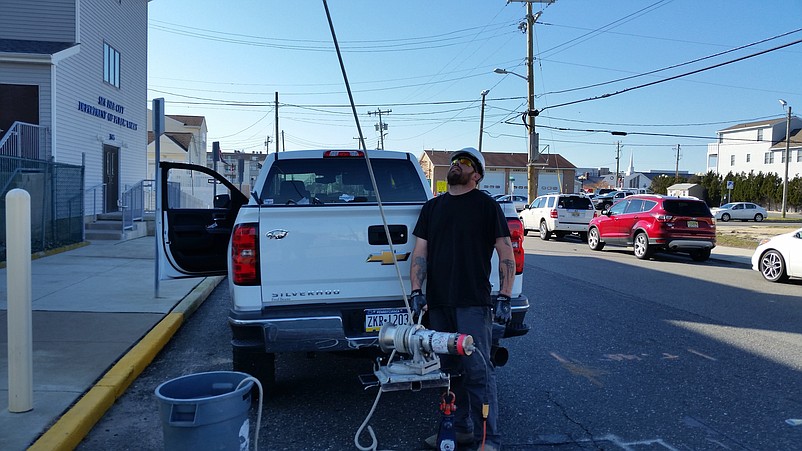 Water tower worker Chris Leclercq peers up as another worker removes communications equipment from the structure.