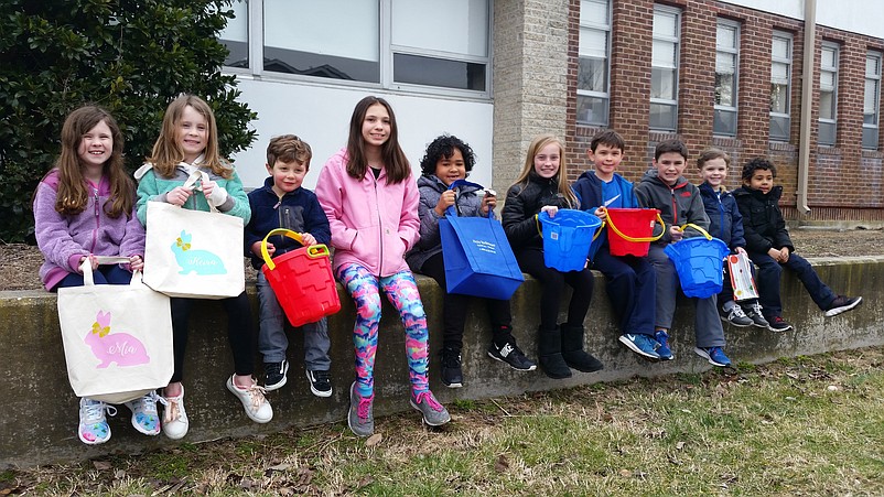 Clutching their buckets and bags, some of the children wait outside the school for the doors to open.