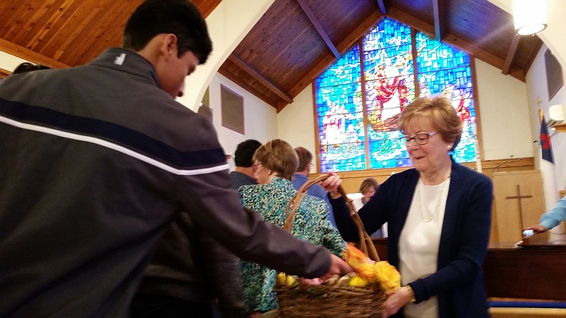 Martie Cook, whose husband, Roy, is the president of the board of trustees at United Methodist Church, hands out roses to the parishioners.