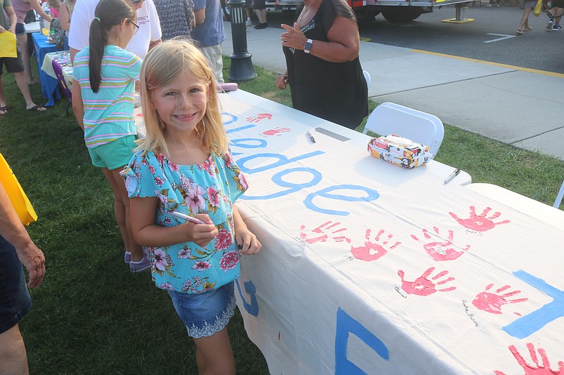 This little girl is all smiles after signing her name to her palm print at the pledge table. 